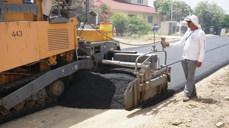 Construction worker operating asphalt paving equipment