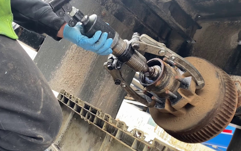 Technician removing wheel hub with hydraulic puller