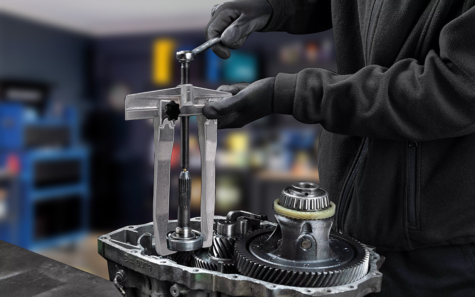 Mechanic using gear puller on transmission sprocket