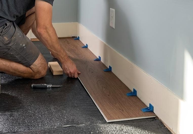 First row of vinyl planks with spacers creating the expansion gap along the wall