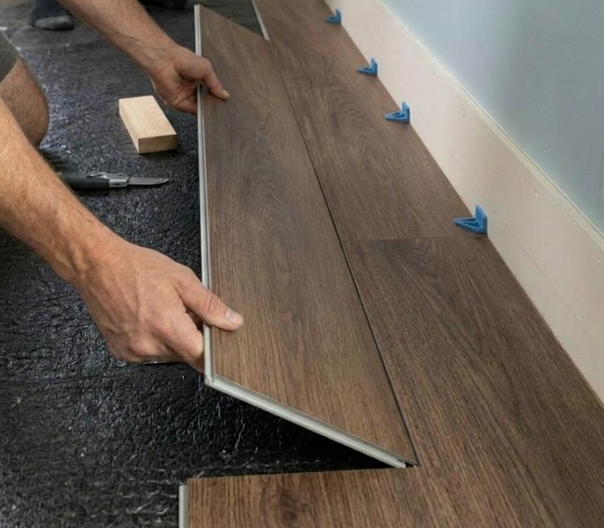Two luxury vinyl planks being clicked together at an angle showing the locking joint