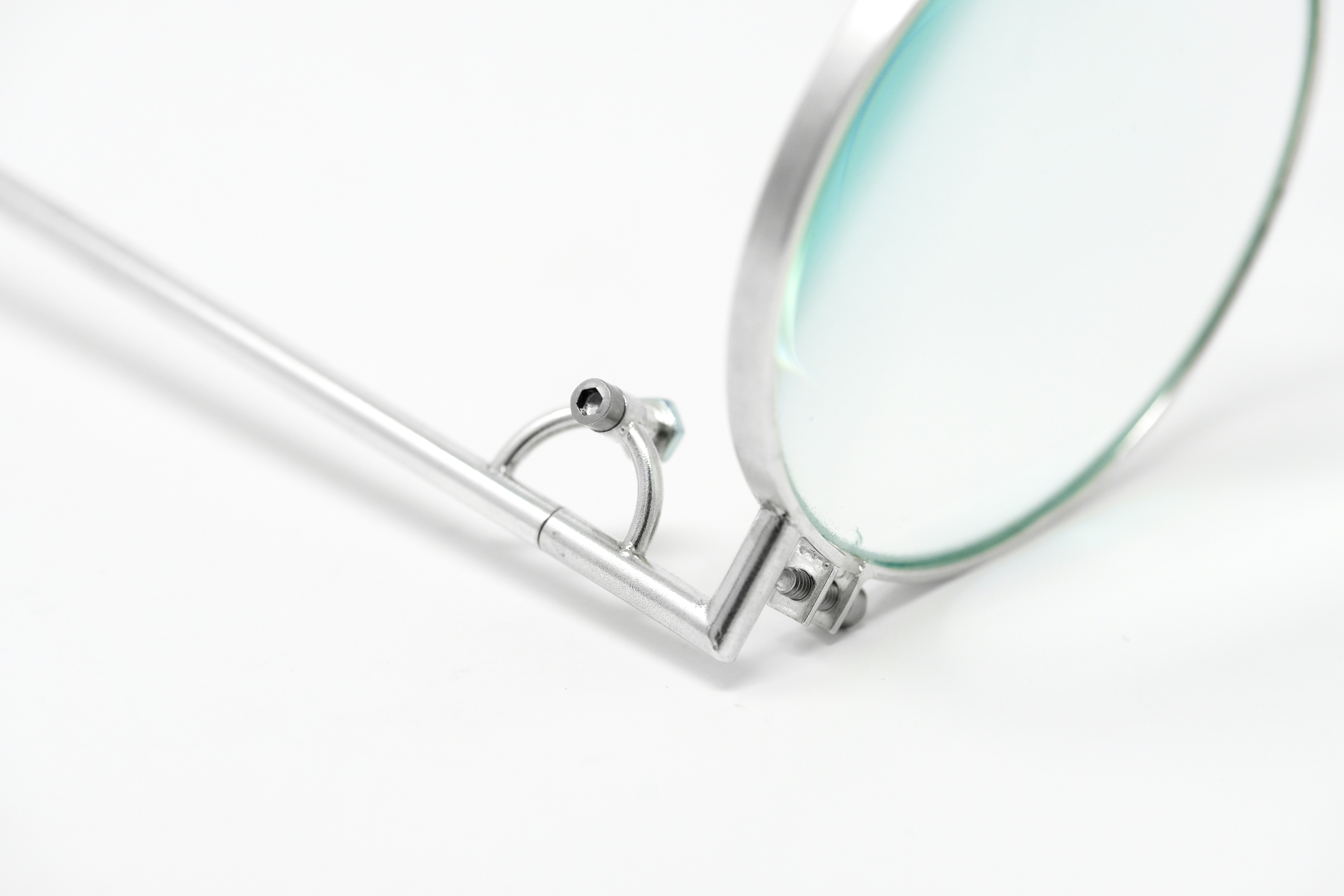 A close-up shot showcasing a high-quality, polished metal eyeglass hinge connecting the frame to the temple.