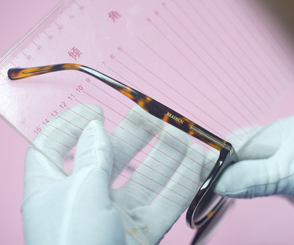 Tortoise acetate temple measured against a ruler during quality control