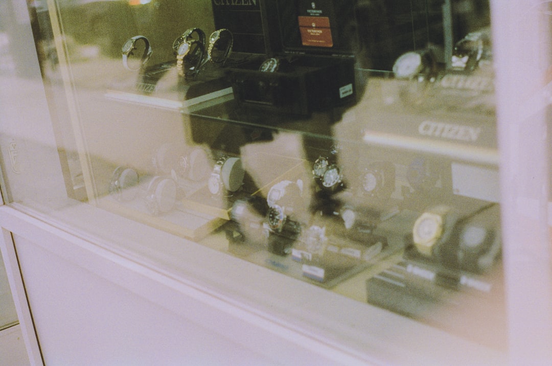 Close-up of an automatic bottle screen printing machine in operation, showing the squeegee pressing ink onto a glass bottle