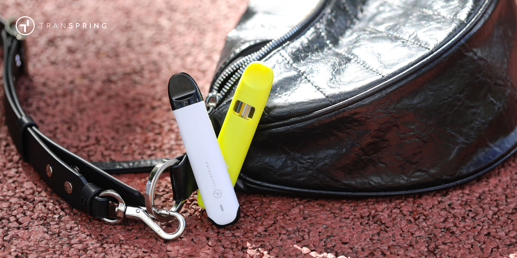 Two disposable vapes resting next to a handbag, illustrating portability