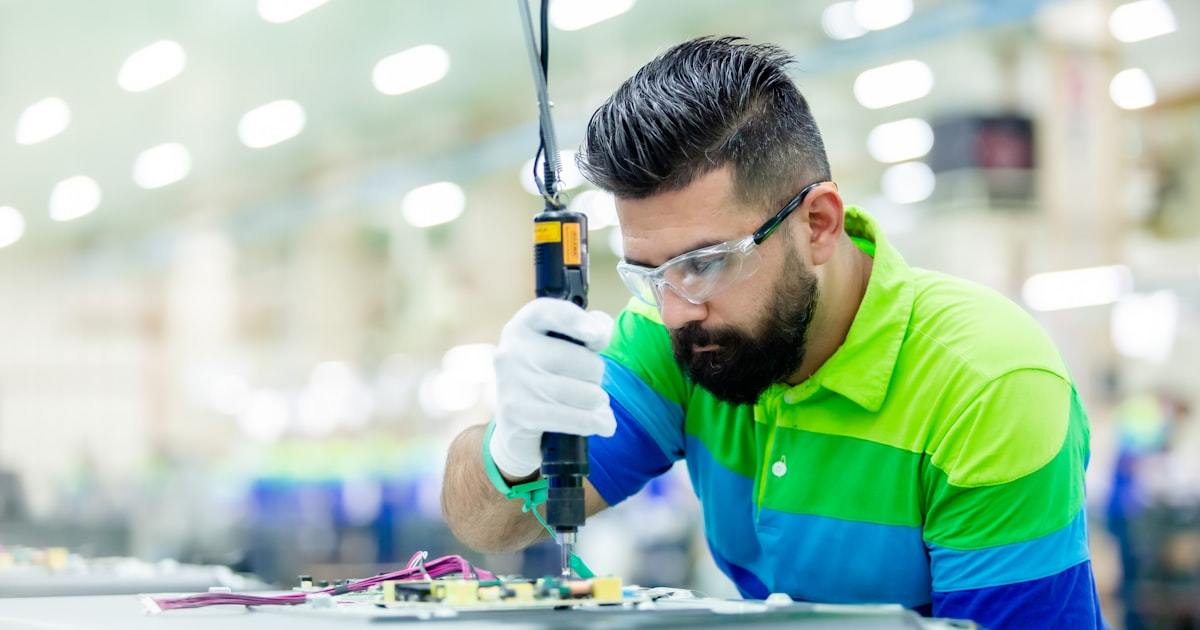 Worker operating production equipment during vape factory quality control inspection