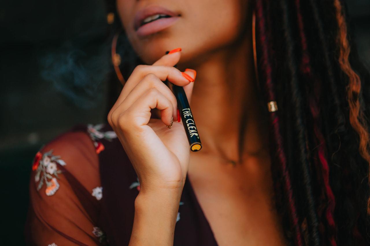 Person holding a tube style THC vape pen during a draw
