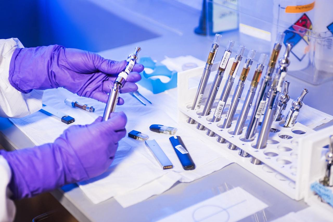 Laboratory technician in gloves inspecting a vape pen during quality control testing
