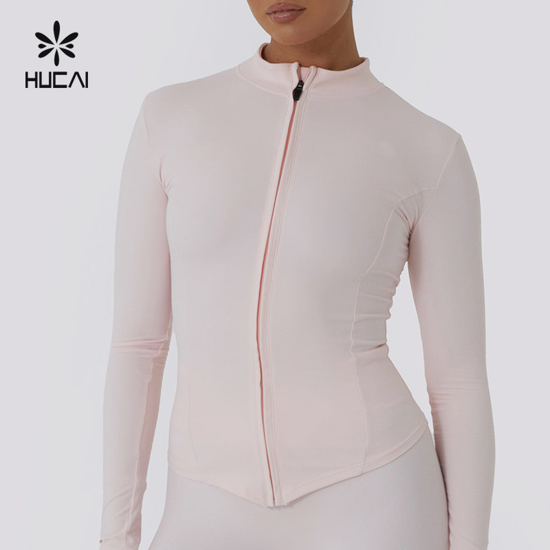 Pale pink zip-front long-sleeve yoga jacket with a center front zipper and shaped side seams, shown on a model