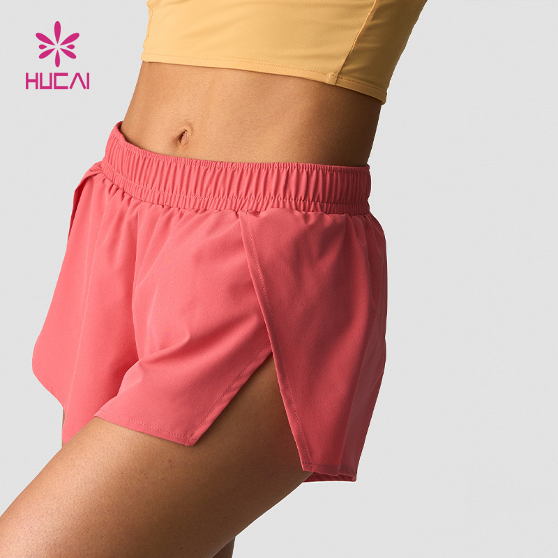 Close view of coral lightweight women's running shorts showing the elasticated waistband, the hem edge and the side split construction