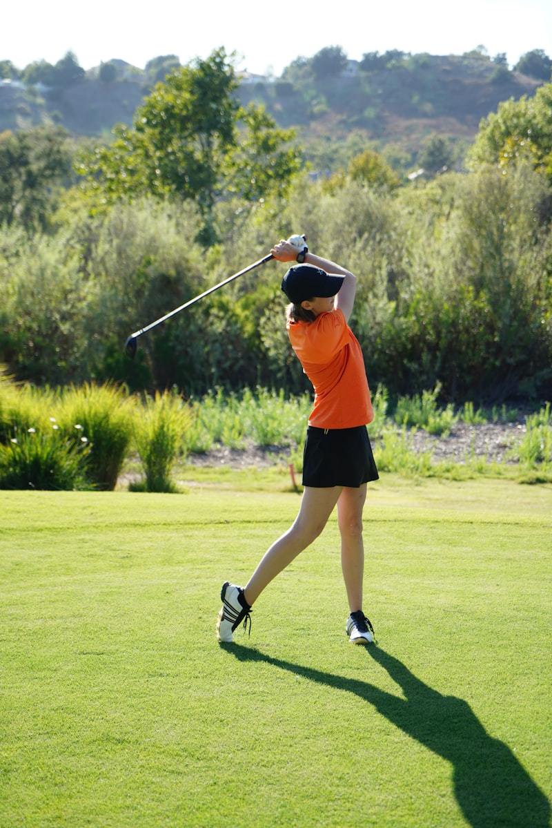 Woman playing golf on a green course wearing athletic golf apparel