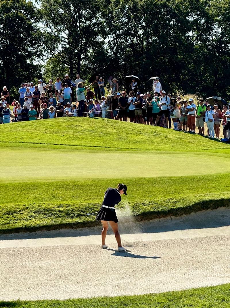 Woman hitting a golf ball in athletic sportswear on a golf course