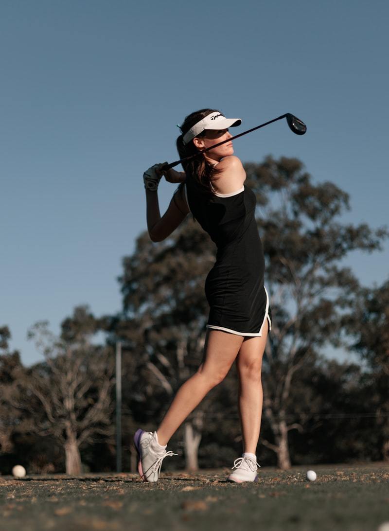 Woman swinging a golf club wearing stretch golf activewear