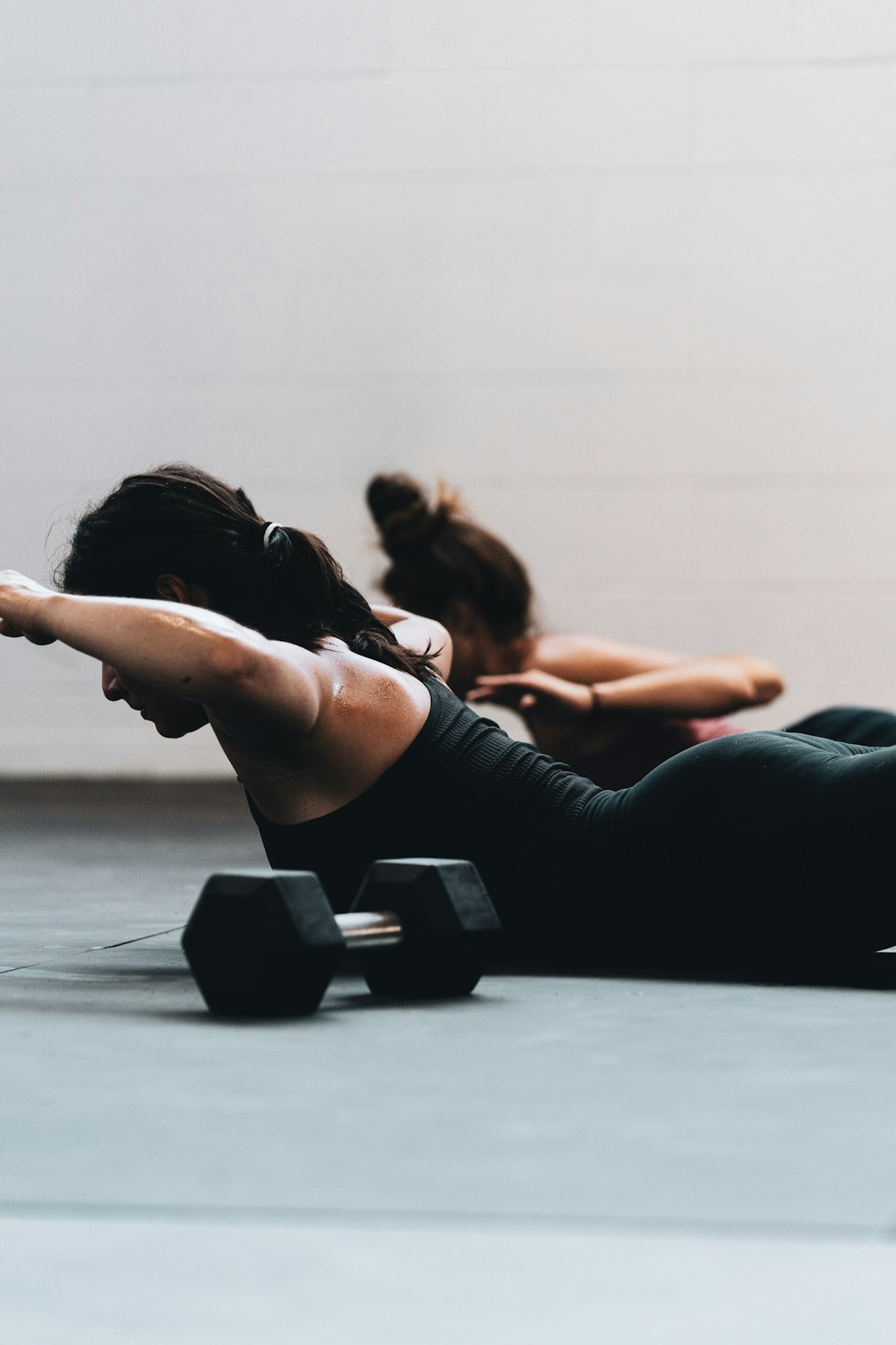 Two women reviewing activewear fit and movement on a studio floor