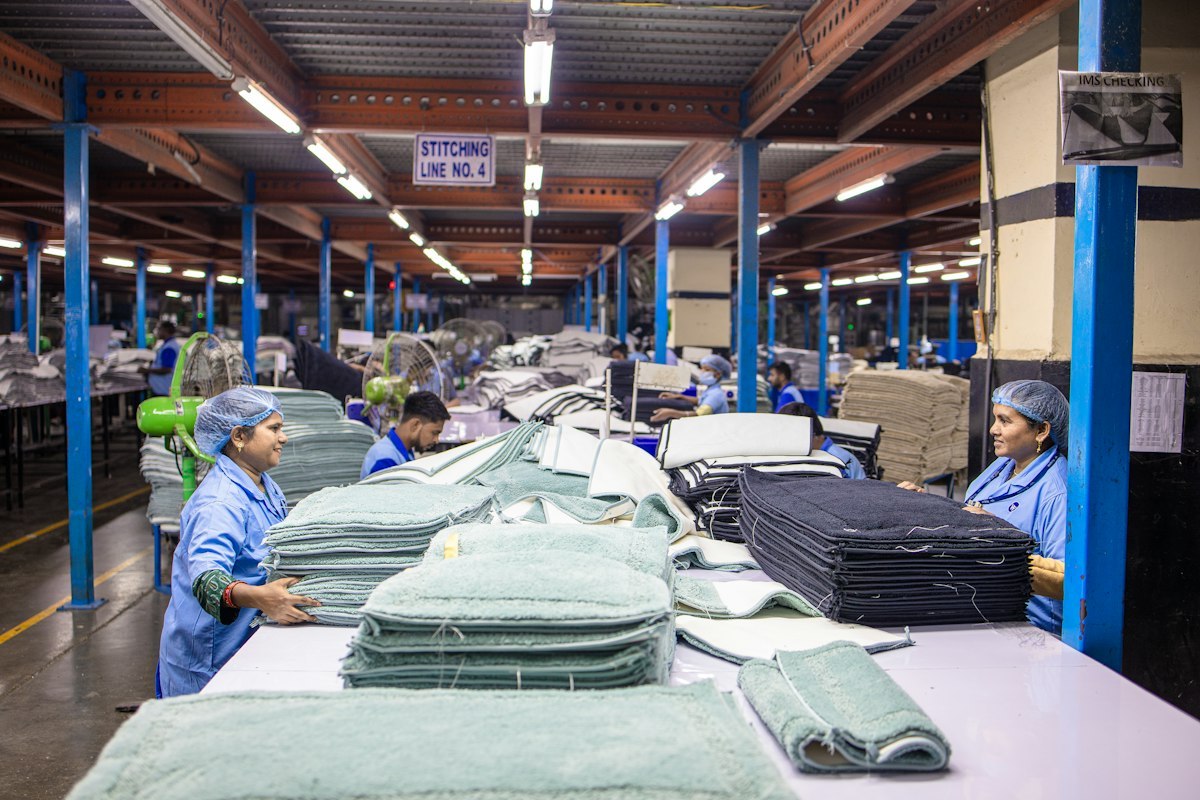 Workers sorting and checking folded fabric panels on a stitching line in a garment factory