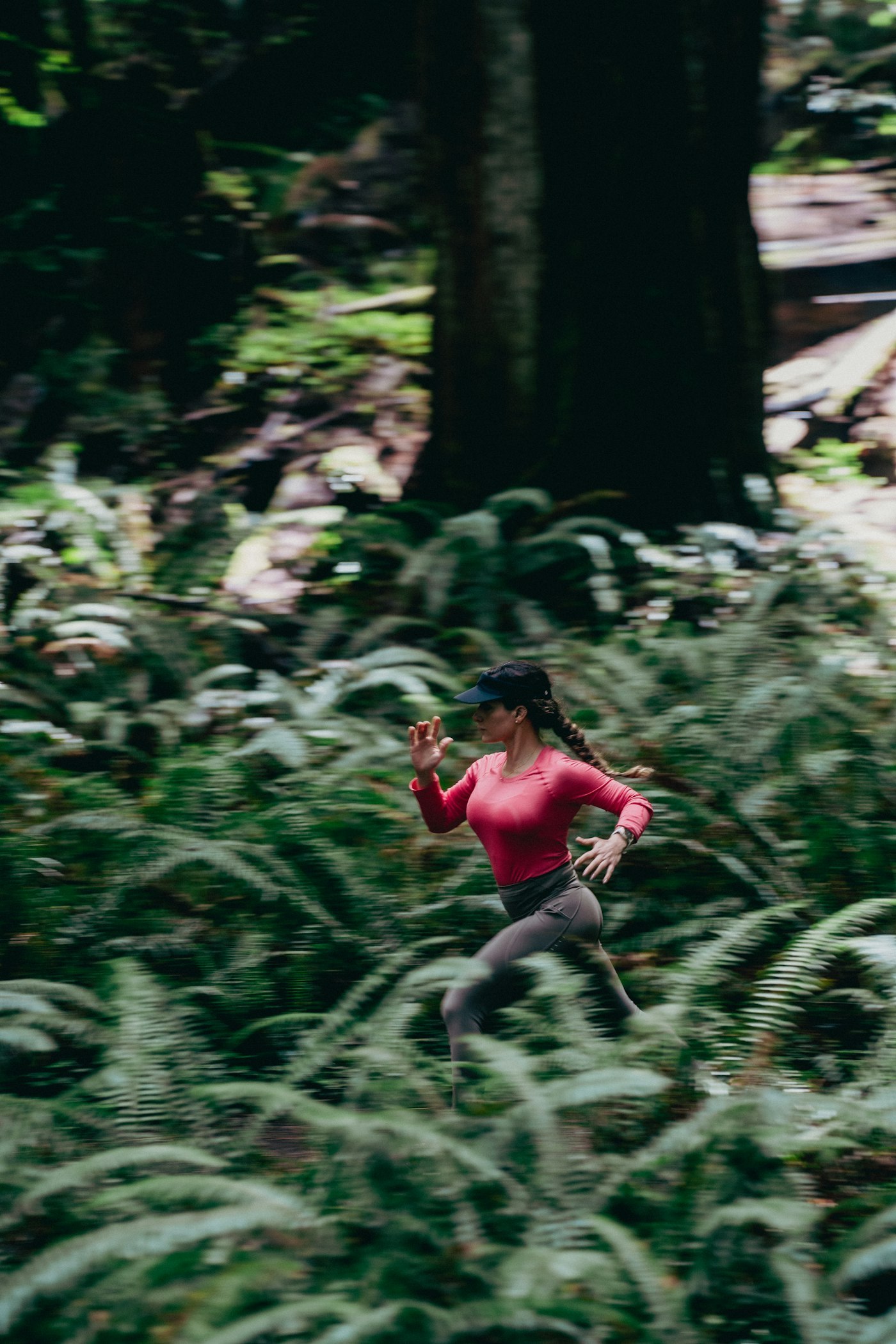 Trail runner wearing a long-sleeve technical top moving through a forest in cool weather