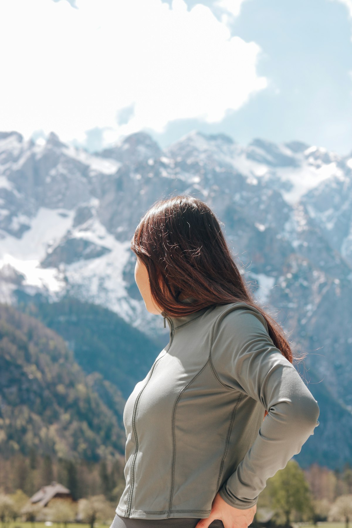 Woman wearing a stretch panel active layer on an alpine trail, illustrating stretch direction and panel construction
