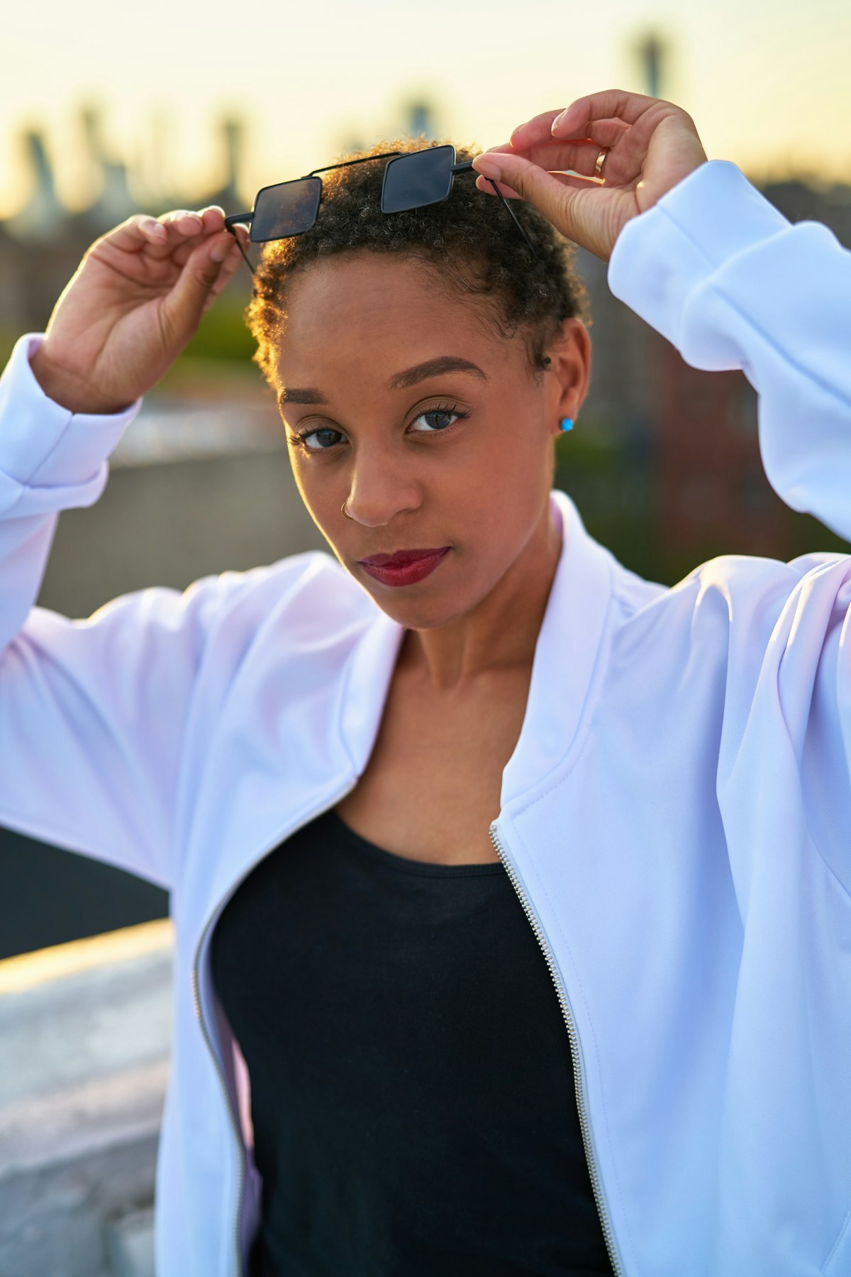 Woman wearing a lightweight jacket over a training top in an urban outdoor setting, illustrating transitional layering for activewear