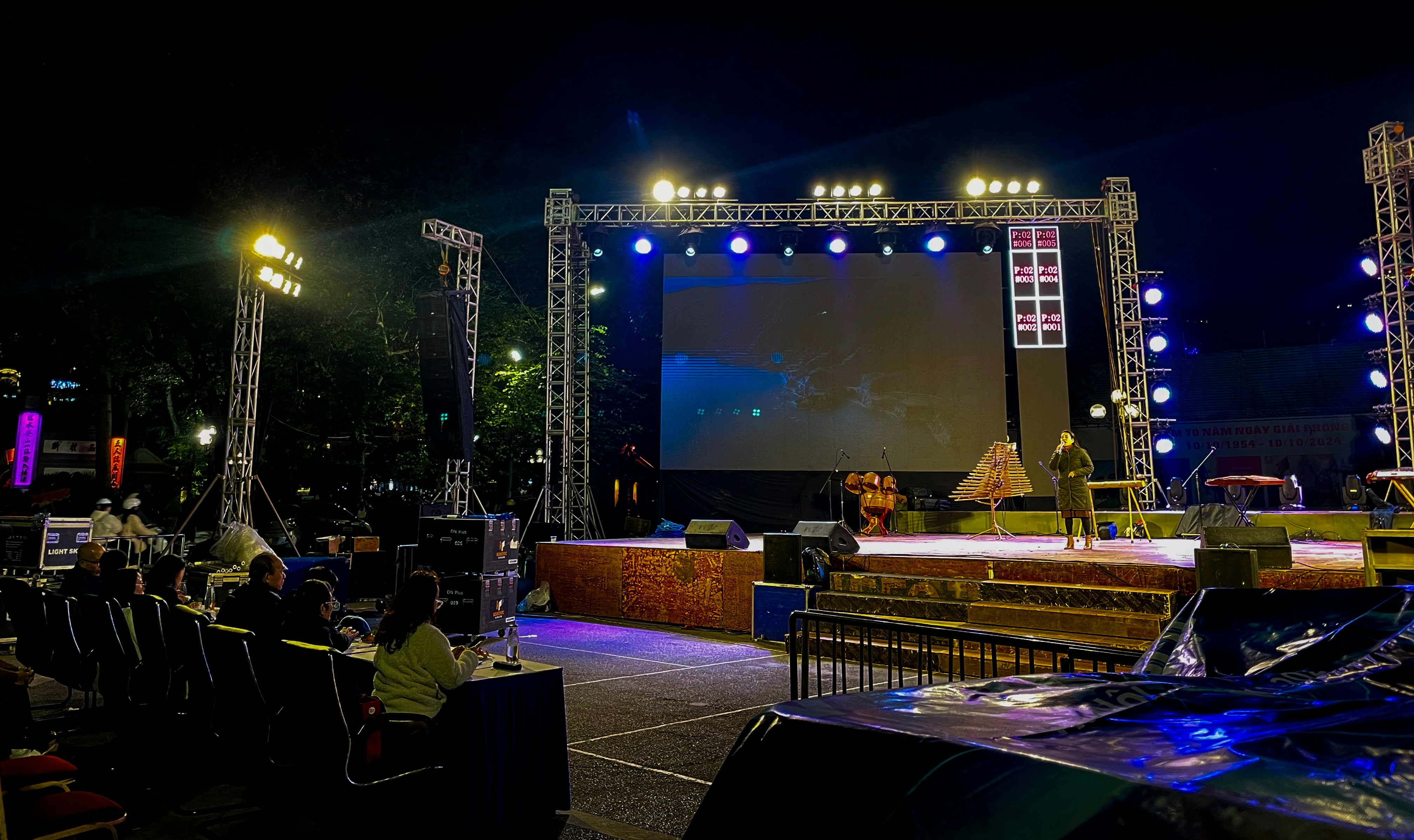 A large line array speaker system flown on the side of an outdoor concert stage