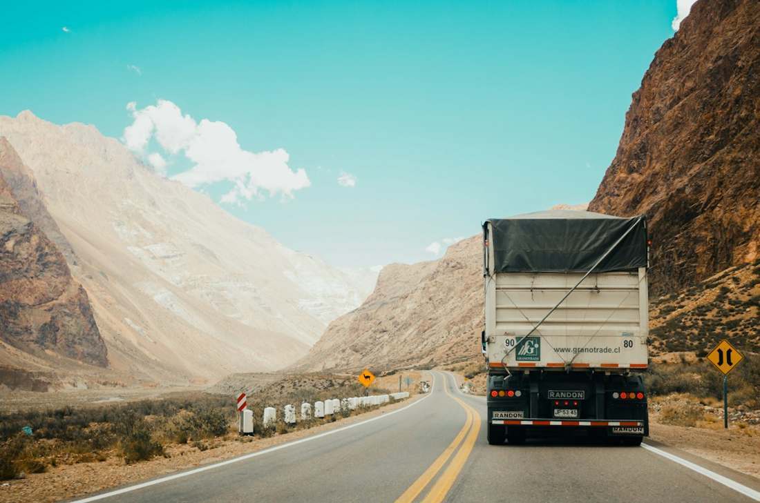 Heavy truck driving on a highway through mountainous terrain
