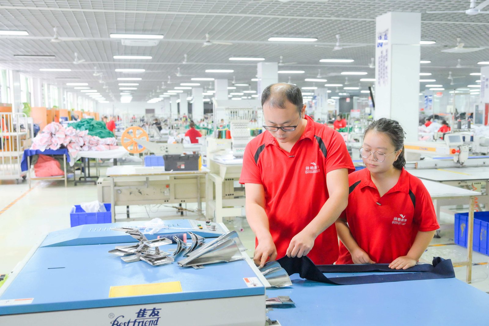 Two workers laying out and checking blue fabric panels on a table