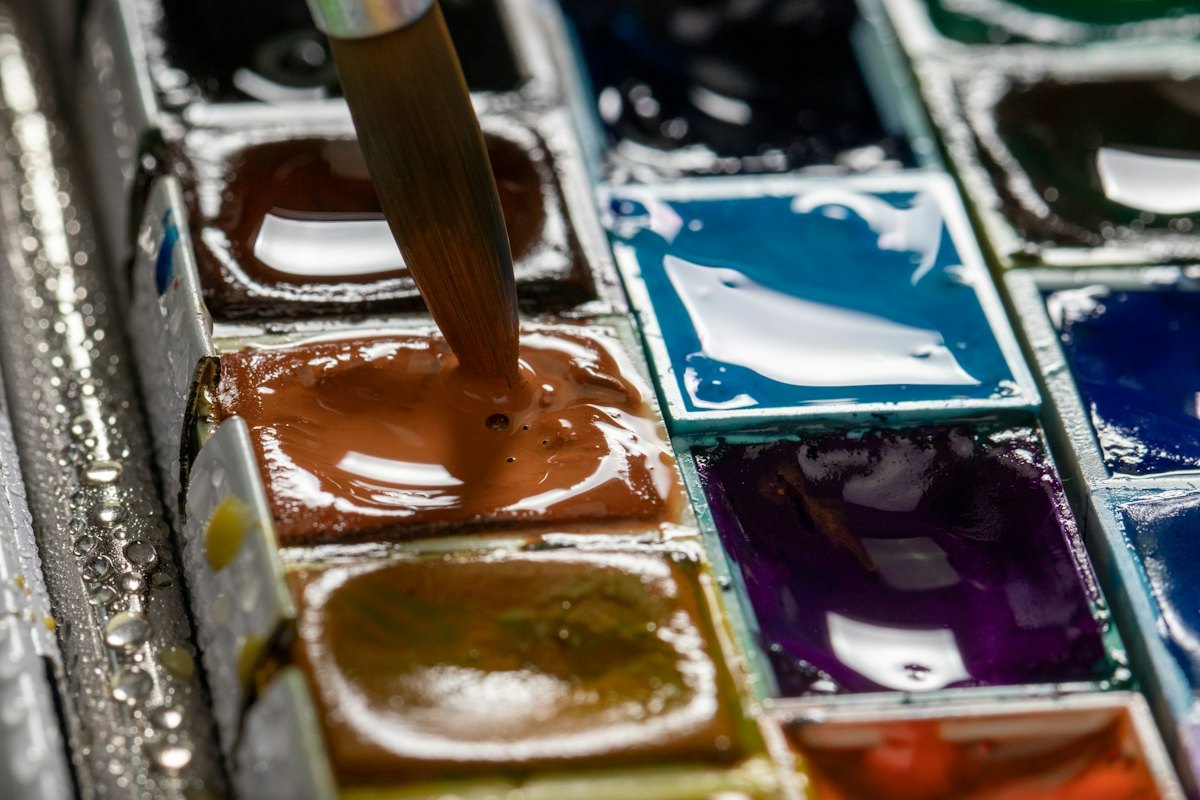 Paint pans and tubes arranged on a work table for comparison