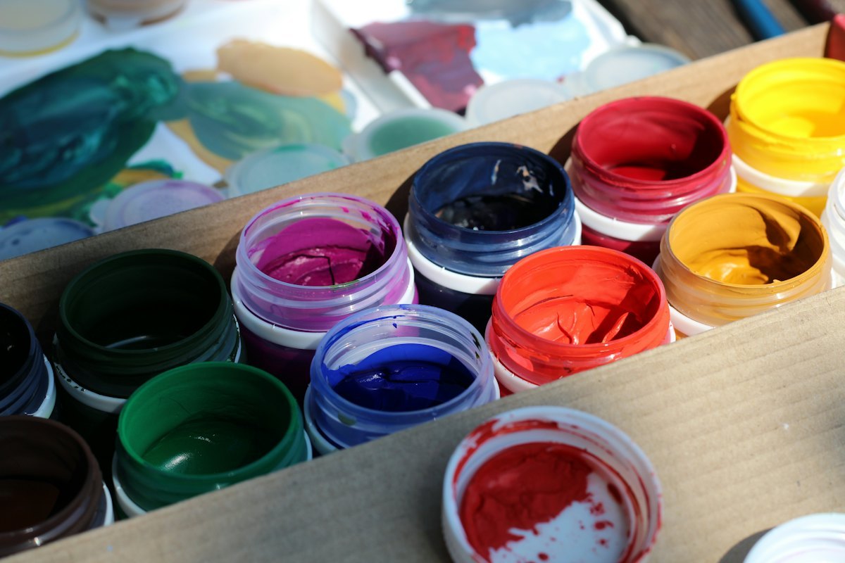 Artist mixing paint colors on a palette in a workshop