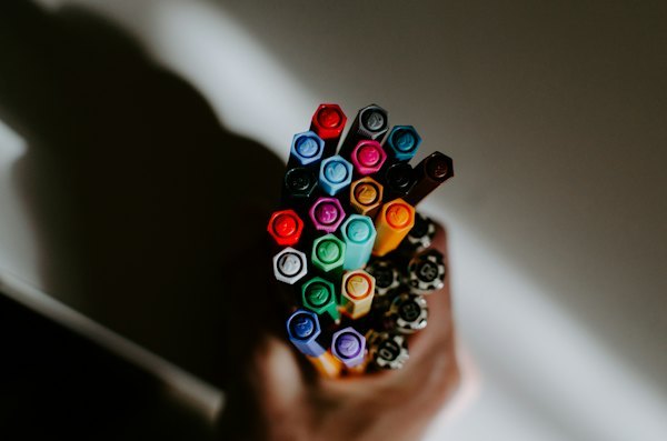 Hand holding a bundle of colored markers under warm light