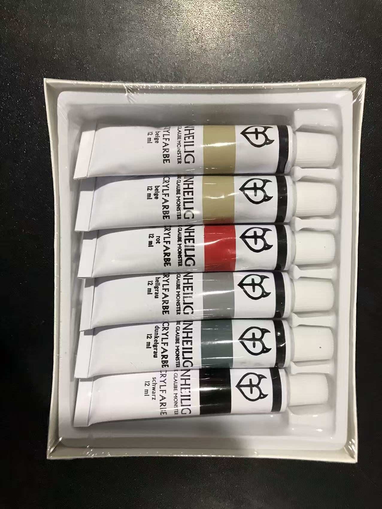 Six Unheilig acrylic paint tubes displayed inside the open carton