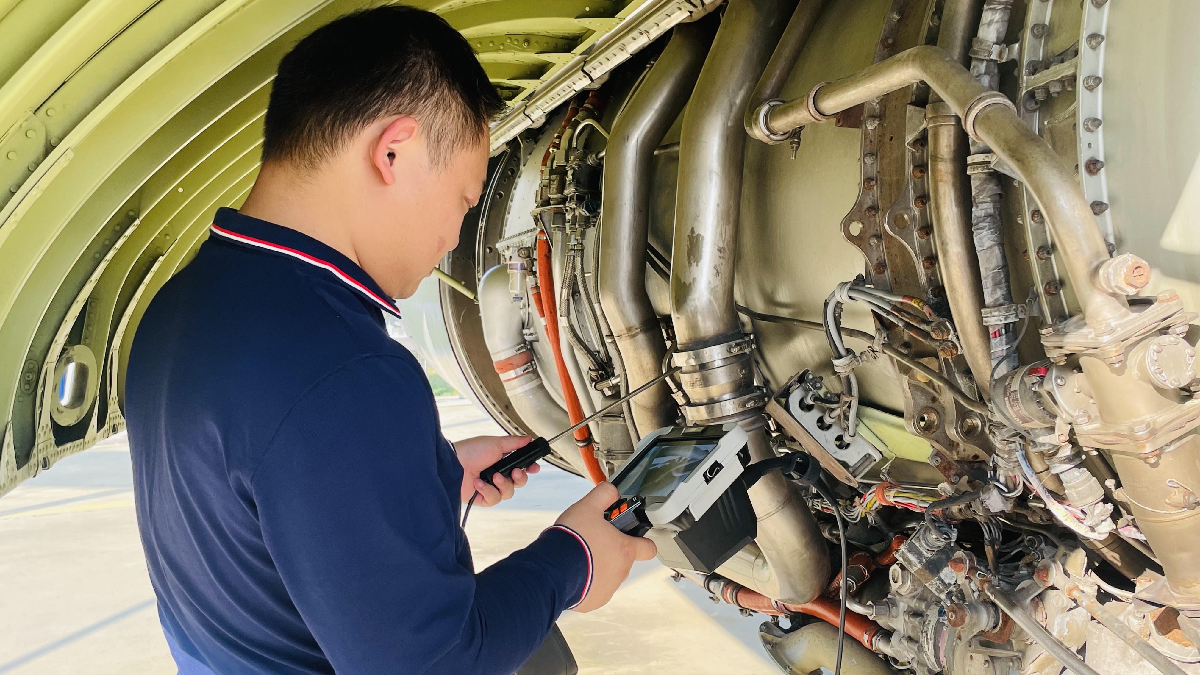 Technician using an industrial borescope on turbine engine