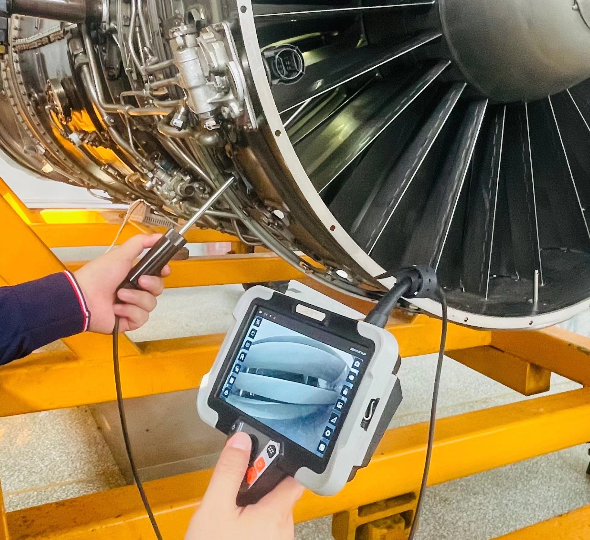 Technician inspecting engine with joystick-controlled videoscope