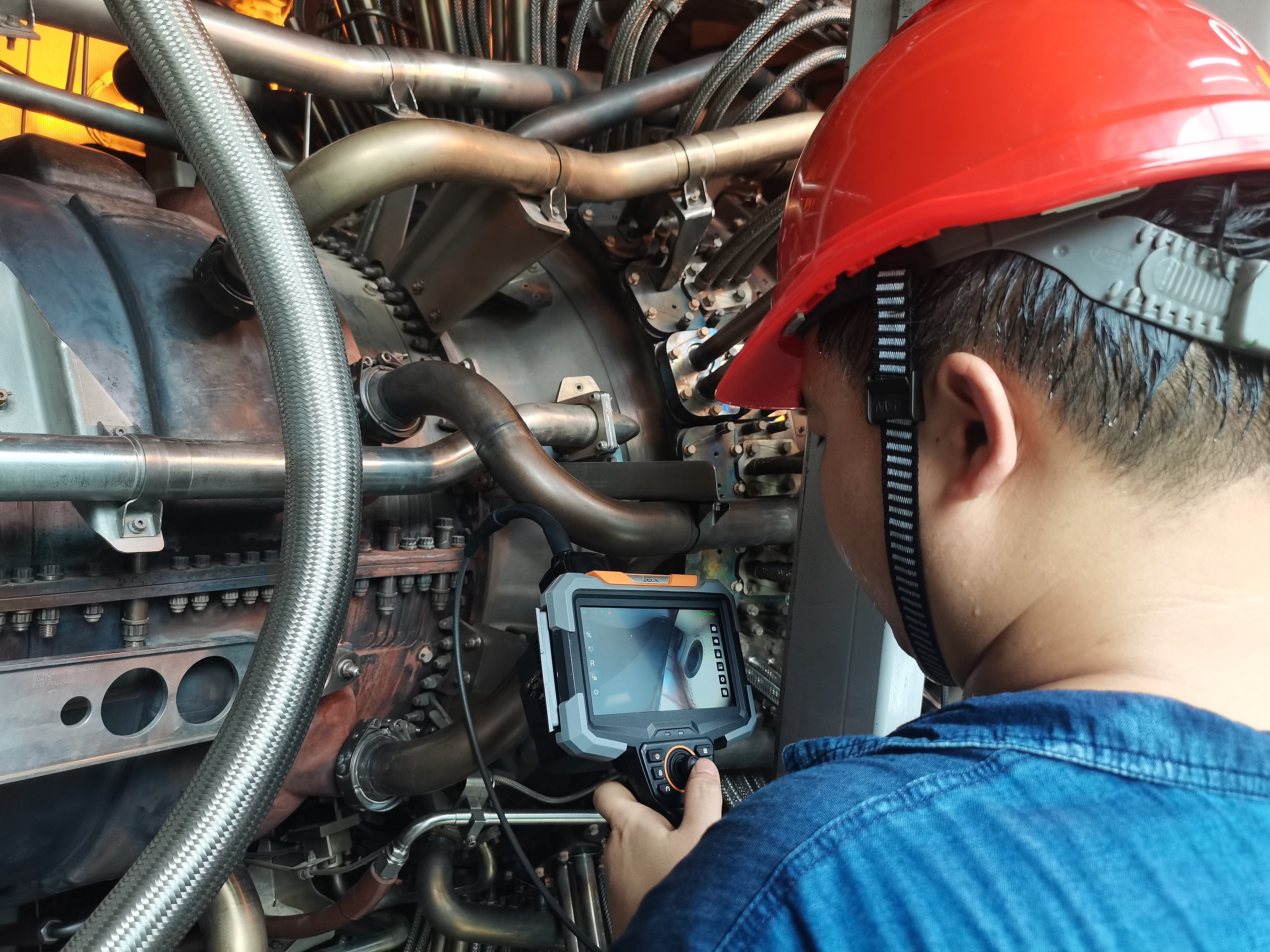 NDT technician using industrial video borescope to inspect steam turbine blade path during planned power plant outage