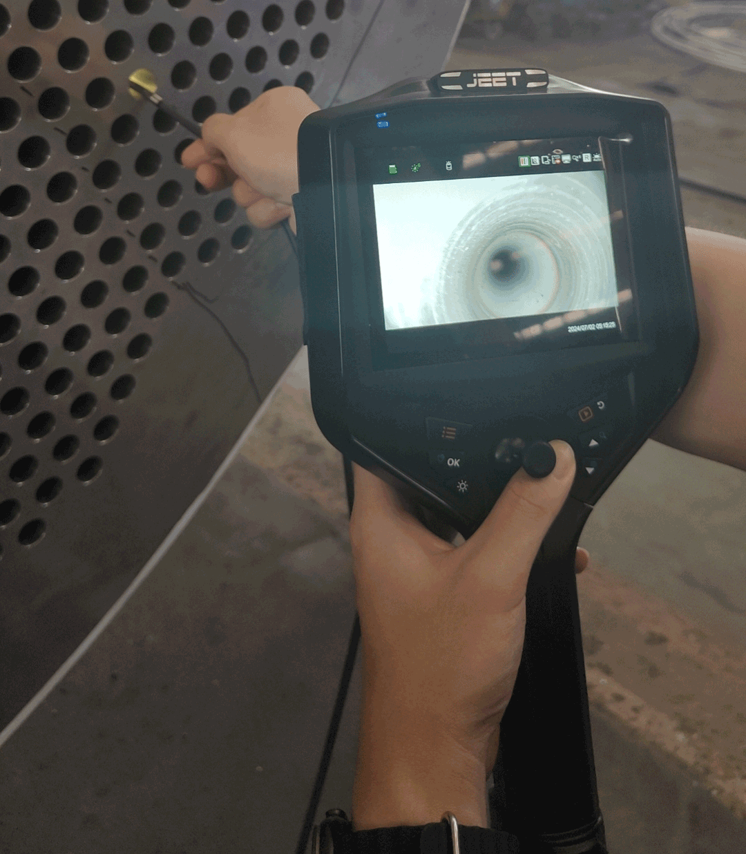 NDT technician using industrial pipe inspection camera to examine heat exchanger tube bundle interior at petrochemical refinery during turnaround