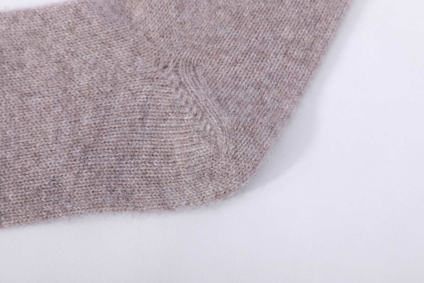 Close-up of the heel and sole area of a knitted cashmere sock, showing the reinforced heel panel and stitch density