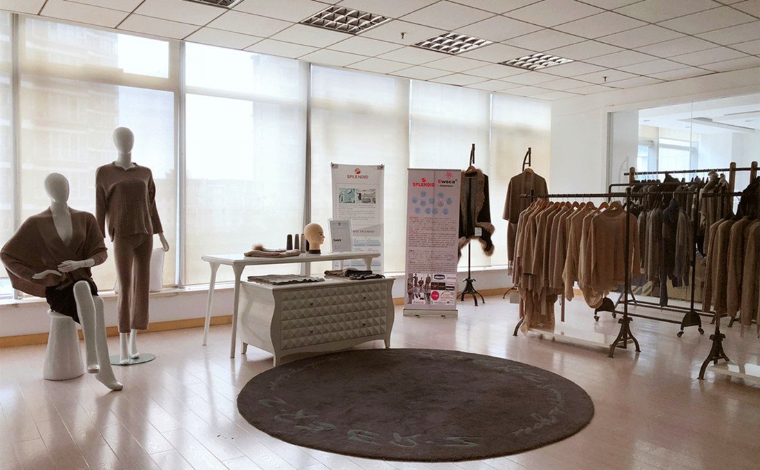 Cashmere knitwear sample room with finished sweaters on rails and mannequins, used to review a turtleneck range and its colourways before an order is confirmed