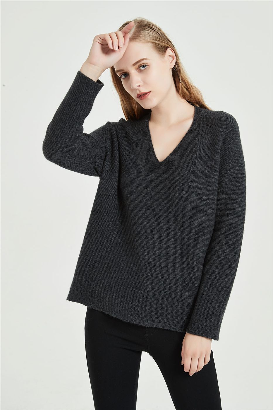 Women's dark grey V-neck cashmere sweater photographed on a studio model, the open neckline that 2026 shoppers are trading for a rollneck