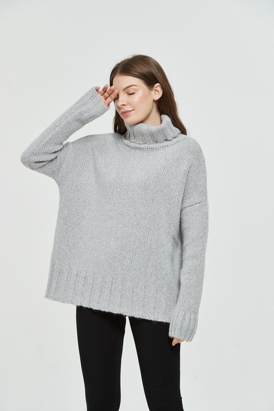Grey oversized cashmere turtleneck showing the rolled collar and ribbed cuff detail on a studio model