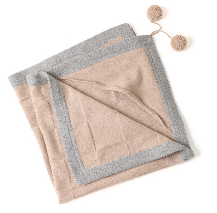 Camel cashmere throw folded to show a hand-worked border stitch and contrasting edge
