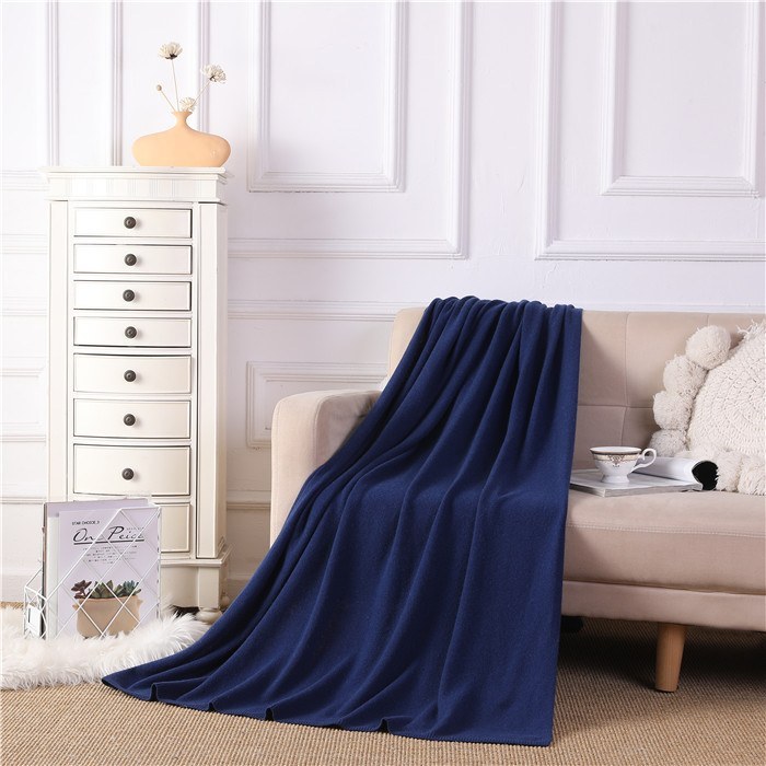 Deep navy cashmere throw draped over the arm of a light sofa in a styled interior