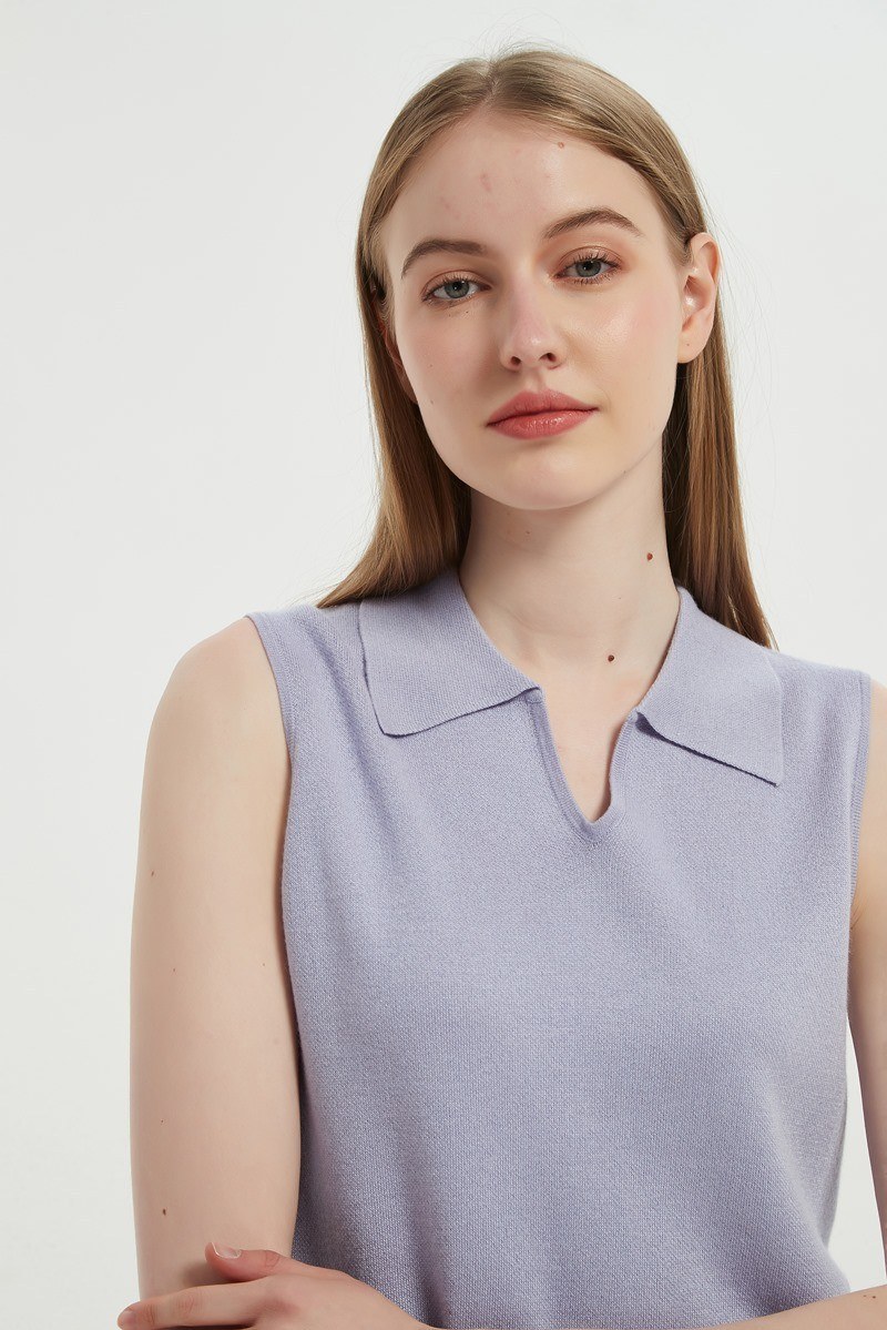 Detail of a sleeveless fine knit top showing the collar point and neckline trim