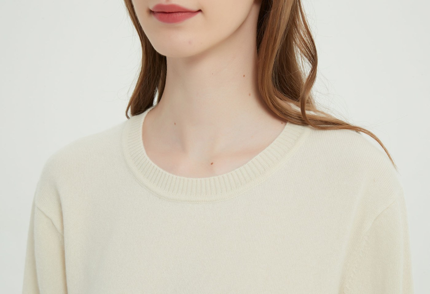 Close view of an undyed oatmeal cashmere crew neck showing the natural fibre shade at the neckline