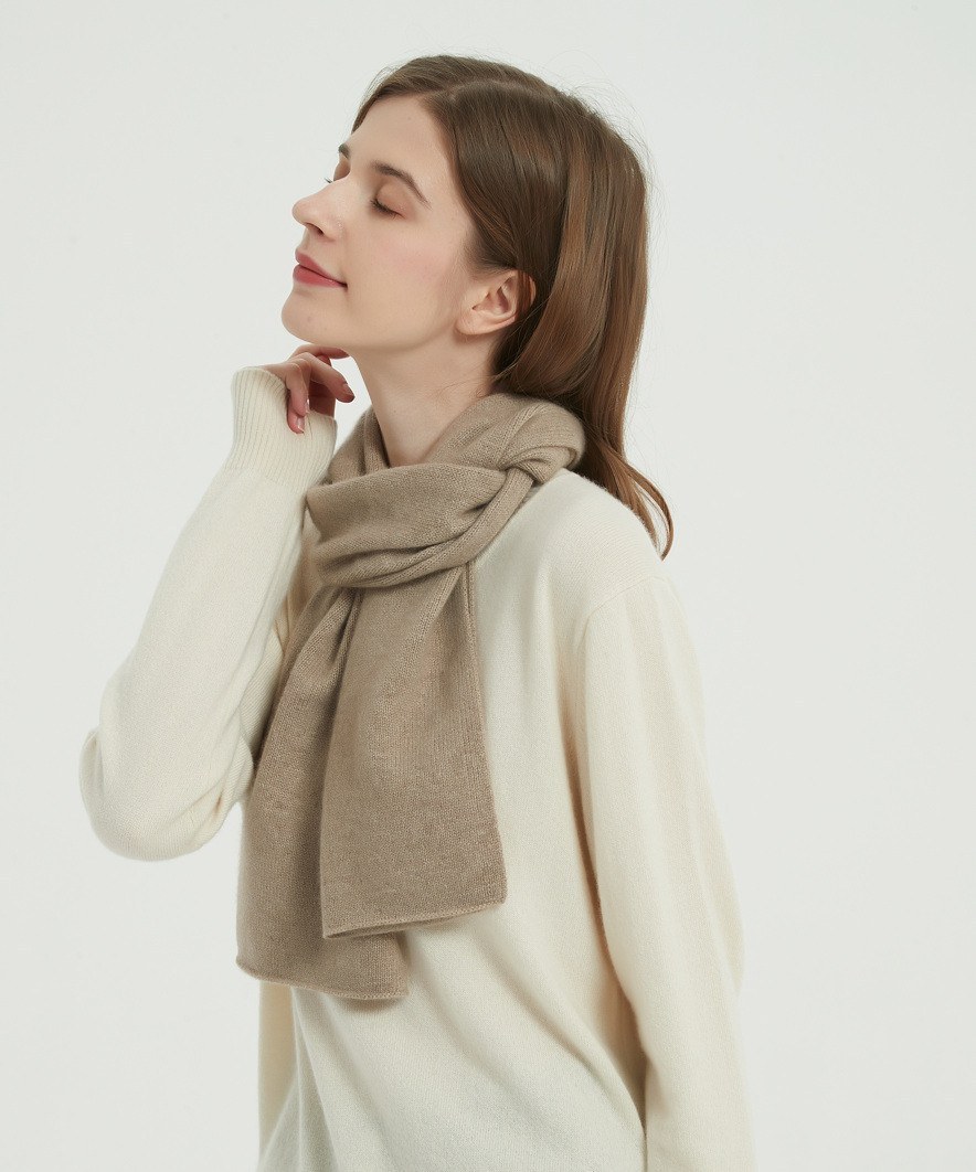 Model wearing a camel brushed cashmere scarf looped around the neck over a cream sweater