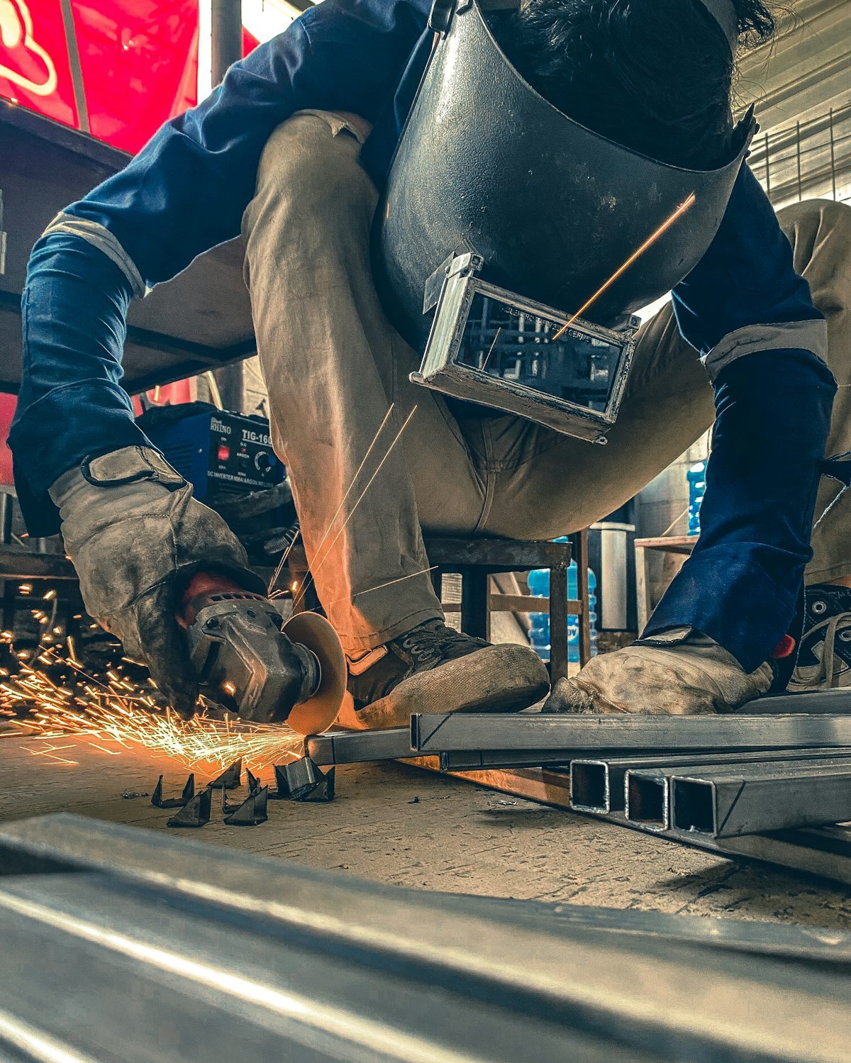 Worker using a grinder in a fabrication workshop