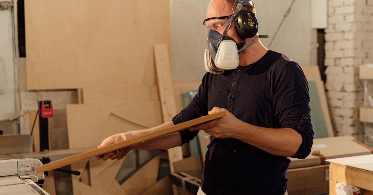 Wood craftsman inspecting plank for custom wooden perfume caps wholesale