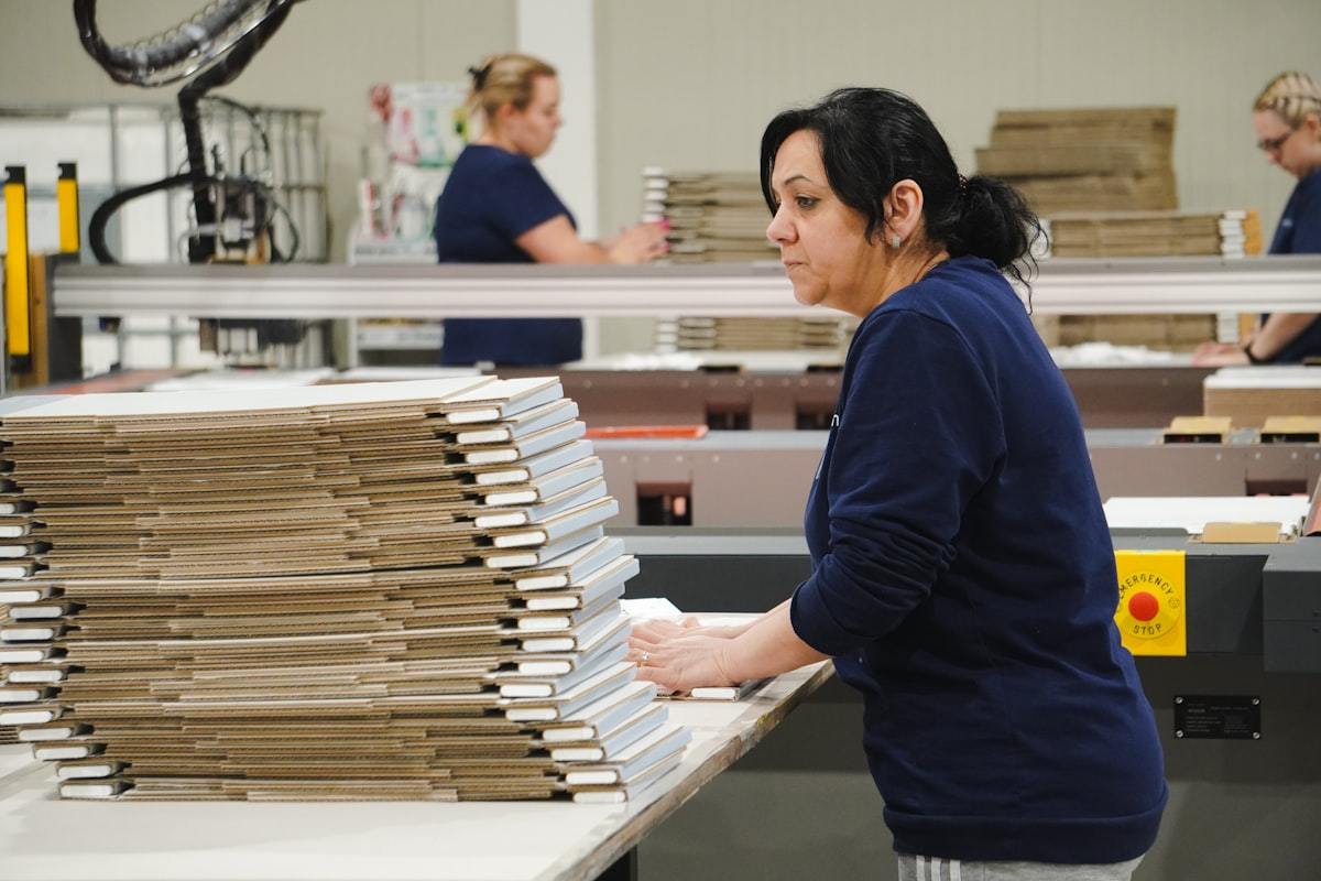 Worker hand-assembling finished perfume gift boxes at the packing bench
