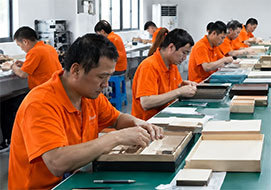 Worker hand-assembling finished perfume gift boxes at the packing bench