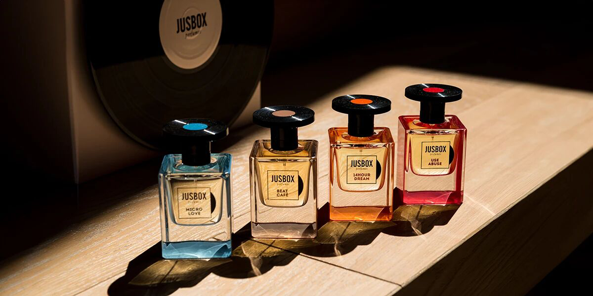 Collection of JUSBOX niche perfumes showcasing unique bottle designs and frosted textures