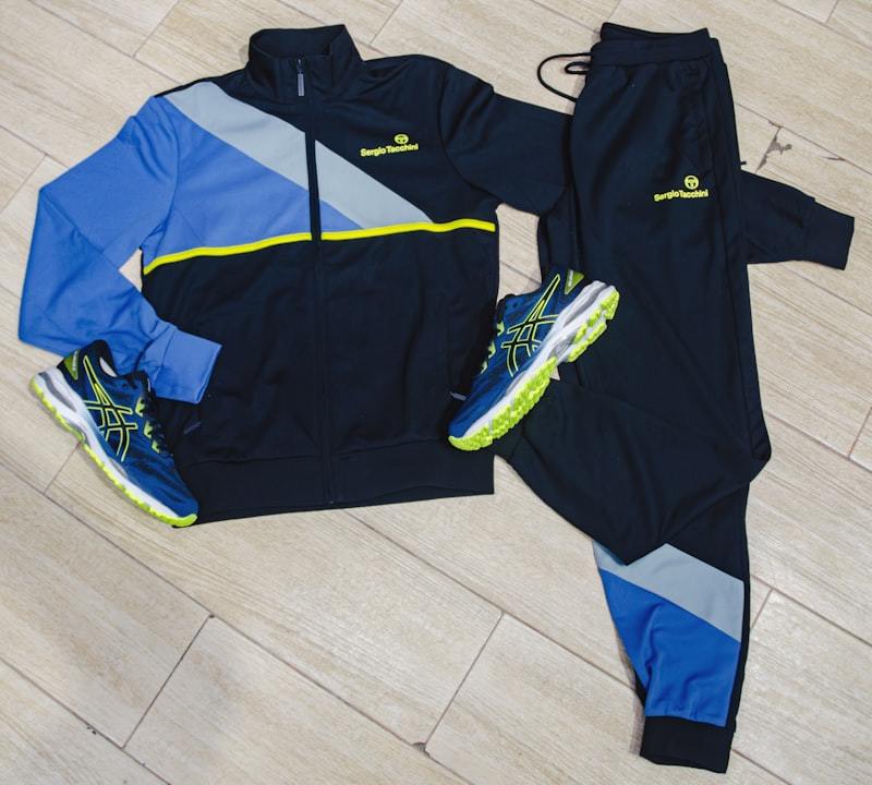 Tracksuits and running shoes laid out on a wooden floor, showing a coordinated multi-SKU men's activewear product family
