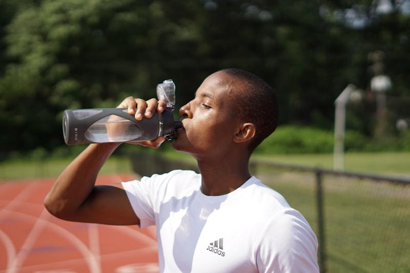 Athlete rehydrating during a training session, part of thermoregulation and fluid balance in warm-weather activewear use