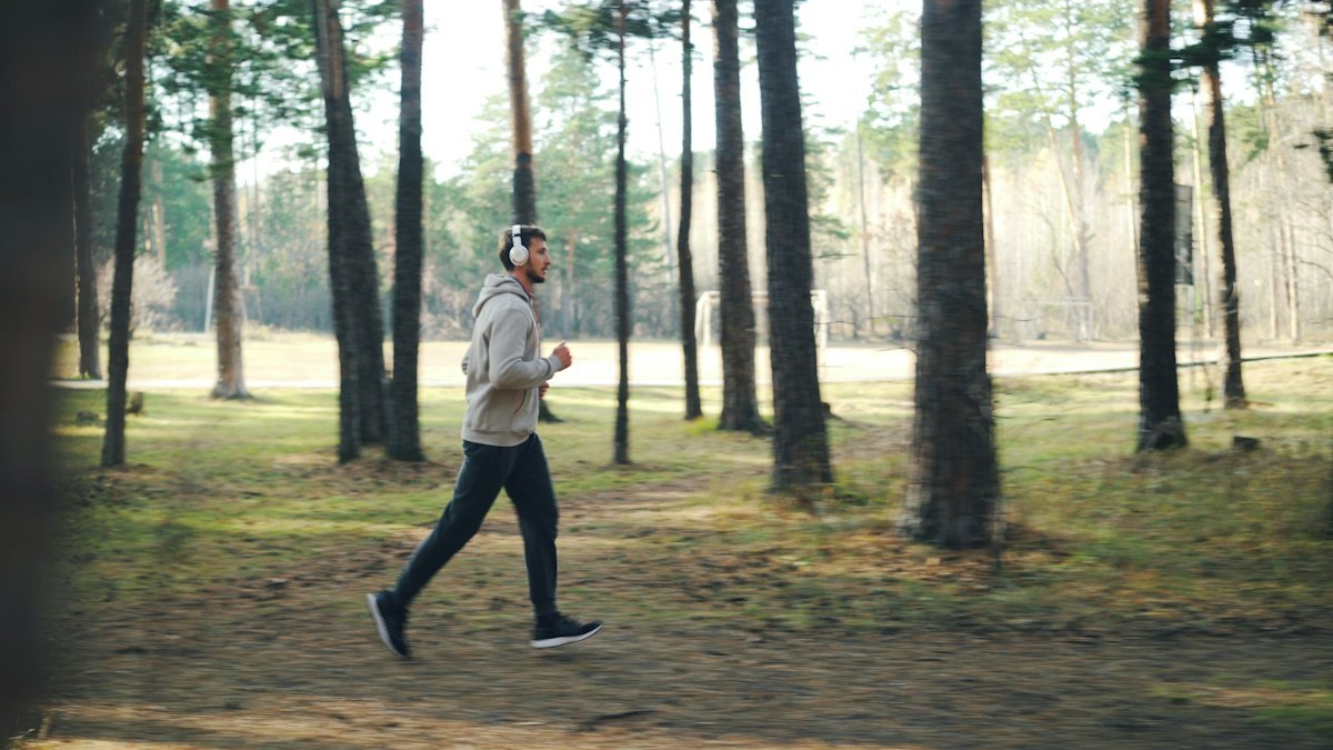 Runner on a forest trail, where abrasion, storage and weather exposure change how running apparel is developed